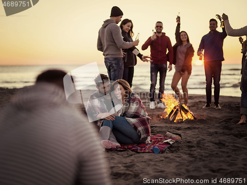 Image of Couple enjoying with friends at sunset on the beach