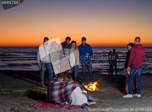 Image of Friends having fun at beach on autumn day