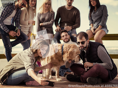 Image of Group of friends having fun on autumn day at beach