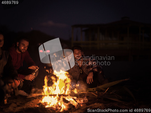 Image of Couple enjoying with friends at night on the beach