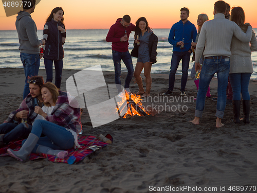 Image of Couple enjoying with friends at sunset on the beach