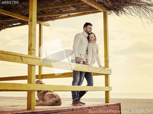 Image of young couple drinking beer together at the beach