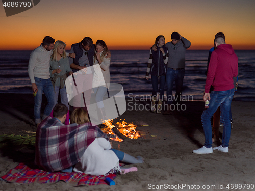 Image of Friends having fun at beach on autumn day