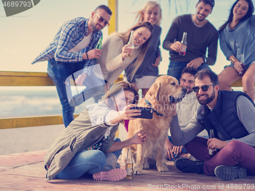 Image of Group of friends having fun on autumn day at beach