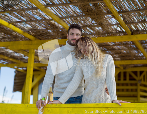 Image of young couple drinking beer together at the beach