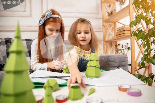 Image of Two little children, girls together in creativity of the house. Happy kids make handmade toys for games or New Year celebration