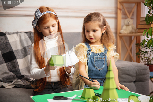 Image of Two little children, girls together in creativity of the house. Happy kids make handmade toys for games or New Year celebration