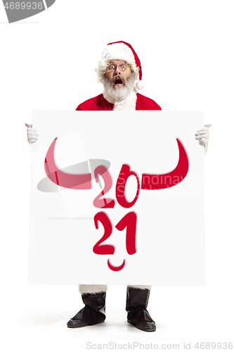 Image of Stylish Santa Claus in traditional costume with 2021 big banner in hands on white studio background