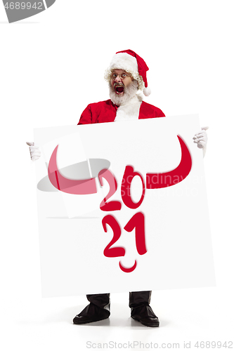 Image of Stylish Santa Claus in traditional costume with 2021 big banner in hands on white studio background