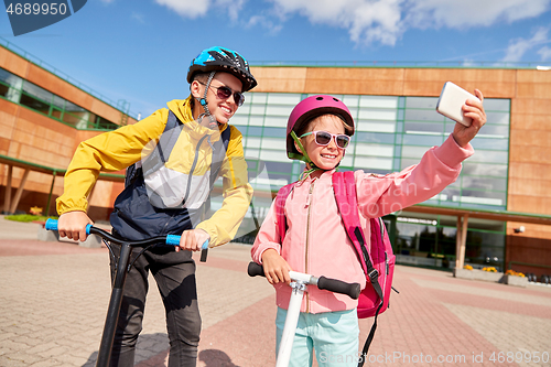 Image of happy school kids with scooters taking selfie