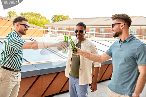 Image of happy male friends drinking beer at rooftop party