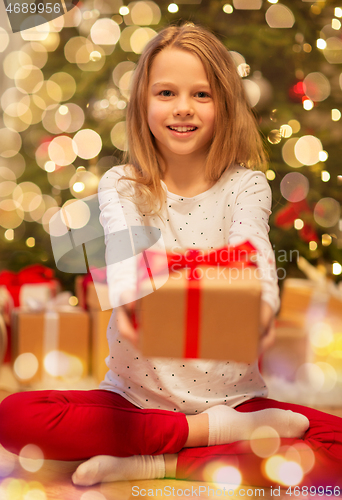 Image of smiling girl with christmas gift at home