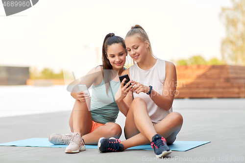 Image of sporty women or friends with smartphone on rooftop