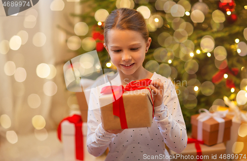 Image of smiling girl with christmas gift at home