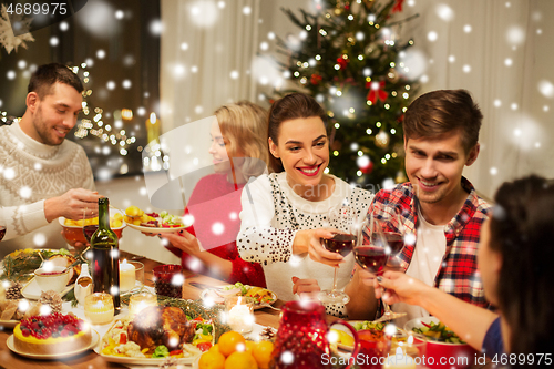 Image of happy friends drinking red wine at christmas party