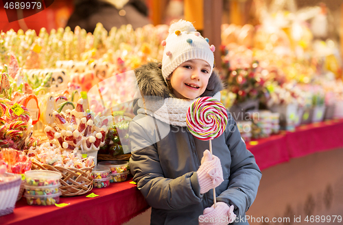 Image of girl with lollipop at christmas market candy shop