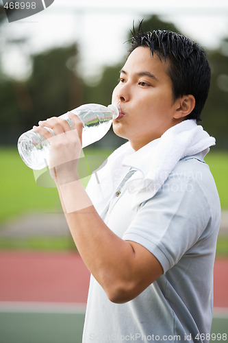 Image of Sporty asian male drinking water