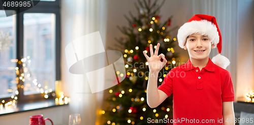 Image of smiling boy in santa helper hat showing ok gesture