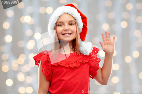 Image of smiling girl in santa helper hat waving hand