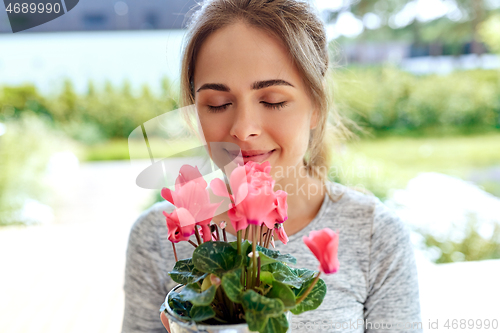 Image of young woman with cyclamen flowers at summer garden