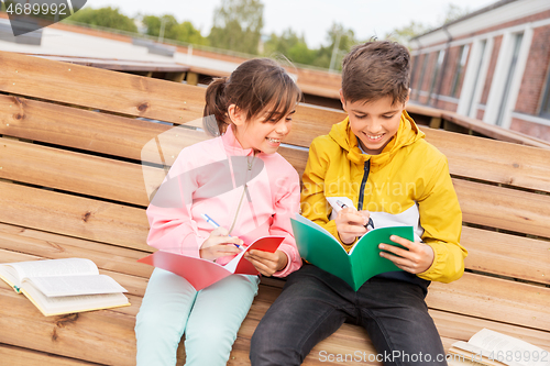 Image of school children with notebooks sitting on bench