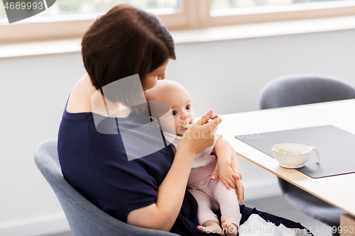 Image of middle-aged mother feeding baby daughter at home