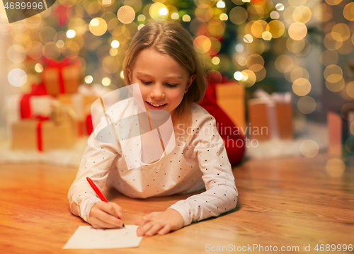 Image of smiling girl writing christmas wish list at home