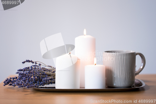 Image of candles, tea in mug and lavender flowers on table