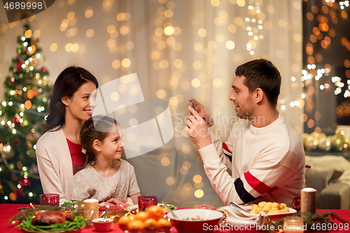 Image of happy family taking picture at christmas dinner