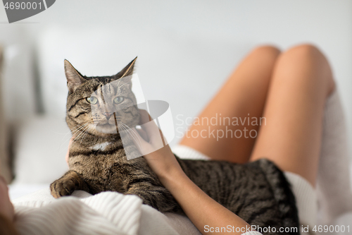 Image of happy young woman with cat lying in bed at home