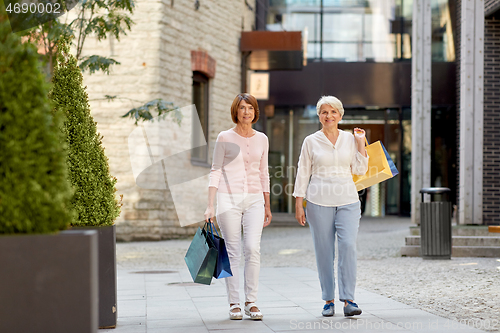 Image of senior women with shopping bags walking in city