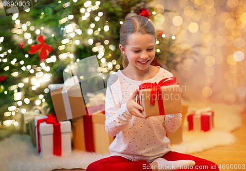 Image of smiling girl with christmas gift at home