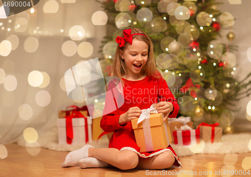 Image of smiling girl with christmas gift at home