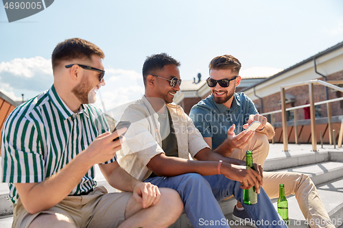 Image of men with smartphones drinking beer on street