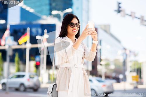 Image of asian woman taking selfie by smartphone in city