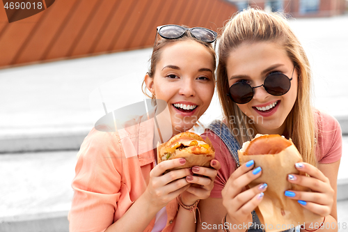 Image of teenage girls or friends eating burgers outdoors