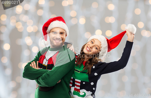 Image of happy couple in christmas sweaters and santa hats