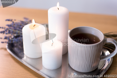 Image of candles, tea in mug and lavender flowers on table