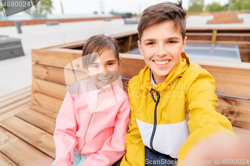 Image of children sitting on street bench and taking selfie