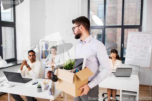 Image of sad fired male office worker with personal stuff