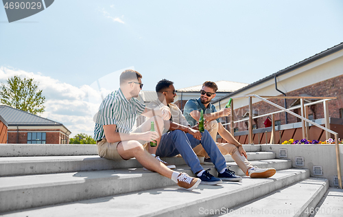 Image of happy male friends drinking beer on street