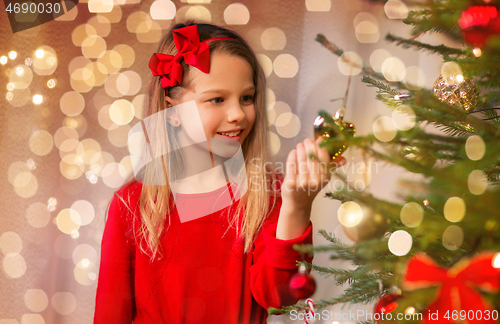 Image of happy girl in red decorating christmas tree