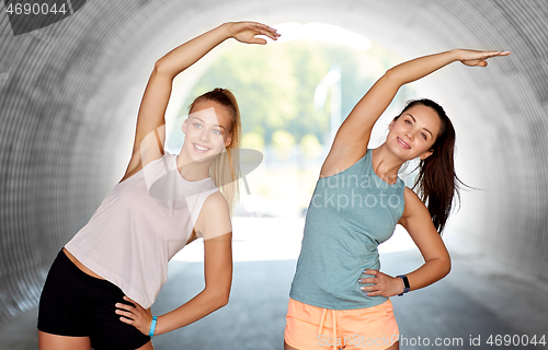 Image of women with fitness trackers stretching outdoors