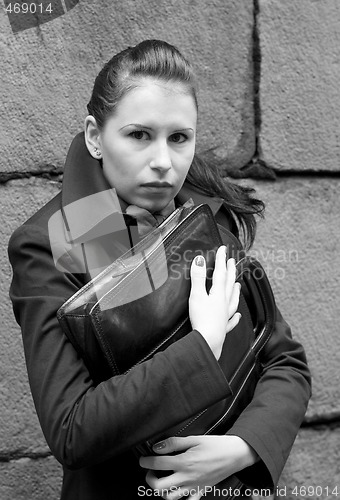 Image of woman in black holding portfolio near brick wall