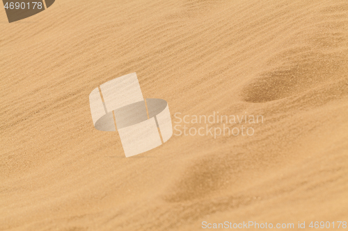 Image of Yellow desert sand with footprints on it.