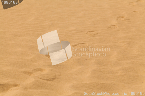 Image of Yellow desert sand with footprints on it.