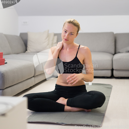 Image of Beautiful blonde woman doing home workout indoors. Woman practice yoga at home. Fit girl using workout tutorials for healthy active lifestyle. Woman using quarantine for home workouts.