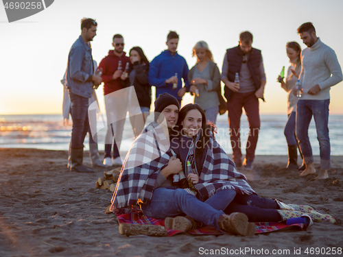 Image of Couple enjoying with friends at sunset on the beach