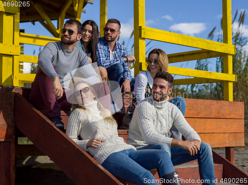 Image of Group of friends having fun on autumn day at beach