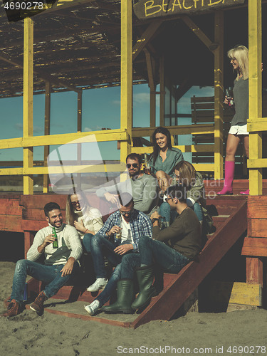 Image of Group of friends having fun on autumn day at beach